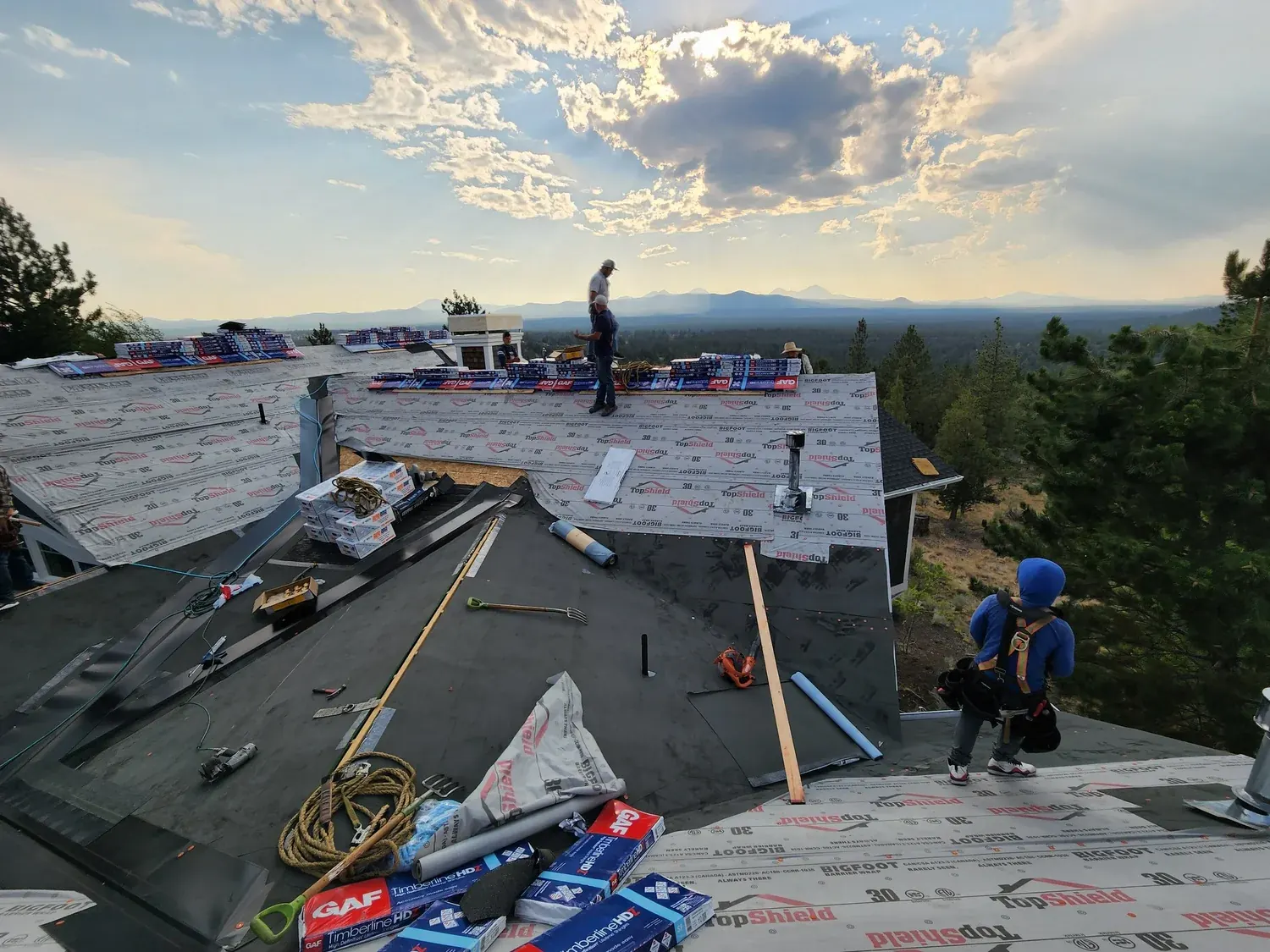 Crew installing underlayment at sunset