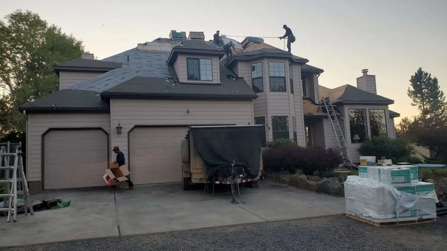 Crew working on a large home with materials staged in the driveway